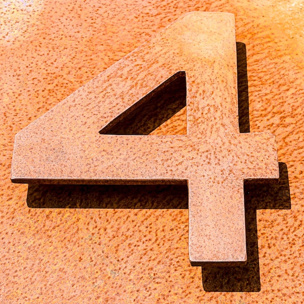 Foto tomada en ángulo alto del número 4 en una superficie de piedra naranja