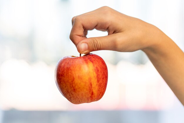 Foto tomada de estudio de cerca de una mano femenina sosteniendo una manzana fresca sobre un fondo blanco manzana roja