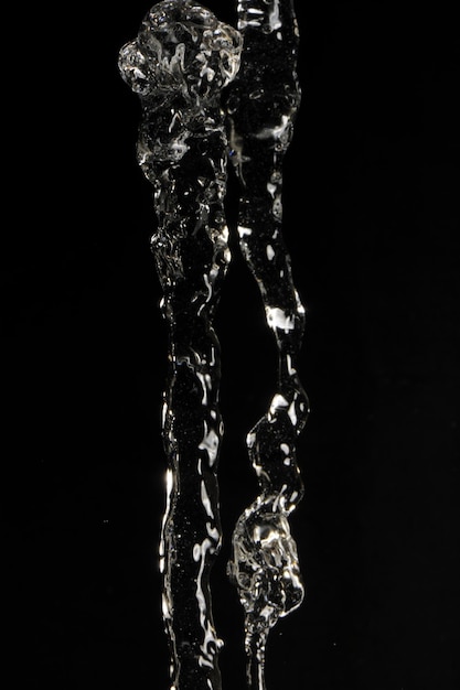 Foto tomada de estudio de verter agua con reflejo de luz contra un fondo negro