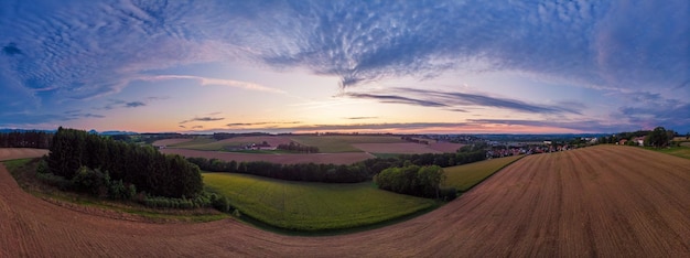 Foto tomada panorámica de un campo agrícola contra el cielo durante la puesta de sol