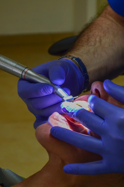Tomada vertical de un dentista trabajando con un paciente bajo las luces en una clínica