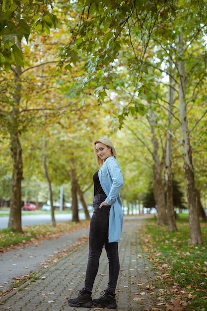 Tomada vertical de una hermosa mujer caucásica en denim posando en el parque