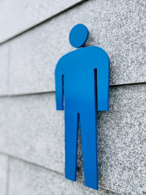 Tomada vertical de un logotipo azul de inodoro masculino en la pared de los baños públicos japoneses