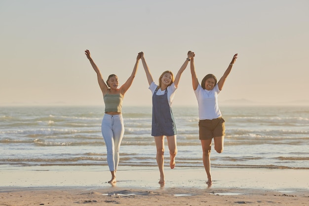 Tomados de la mano de amigos y mujeres en la playa, saltan juntos y se unen o se aman al aire libre en las vacaciones de verano. Viajar, mujeres jóvenes o damas, disfrutar de vacaciones junto al mar para viajes de niñas y conectarse en vacaciones.