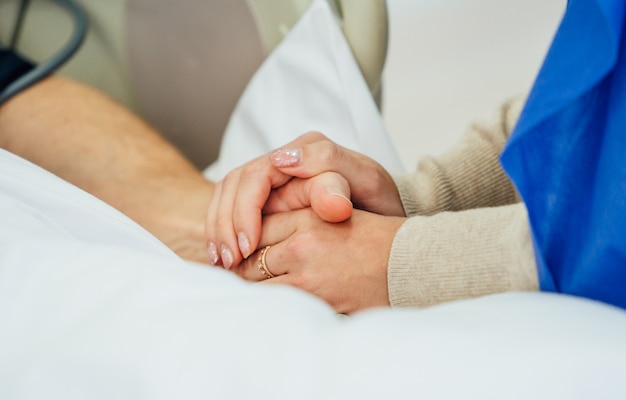 Tomados de la mano del paciente en un hospital. Ayuda familiar De cerca. Apoyo.