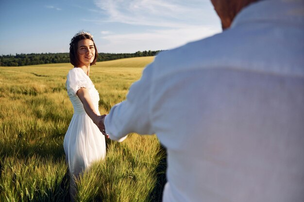 Tomados de las manos Pareja recién casada Juntos en el majestuoso campo agrícola en un día soleado