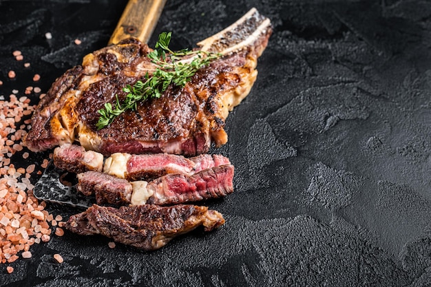 Tomahawk asado en seco o bistec de carne de vaquero en una cuchilla de carne Fondo negro Vista superior Espacio de copia