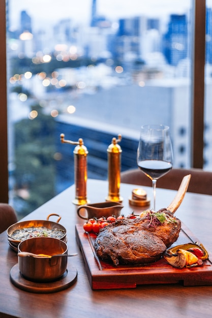 Tomahawk bistec con puré de patata, queso espinaca al horno y salsa de salsa.