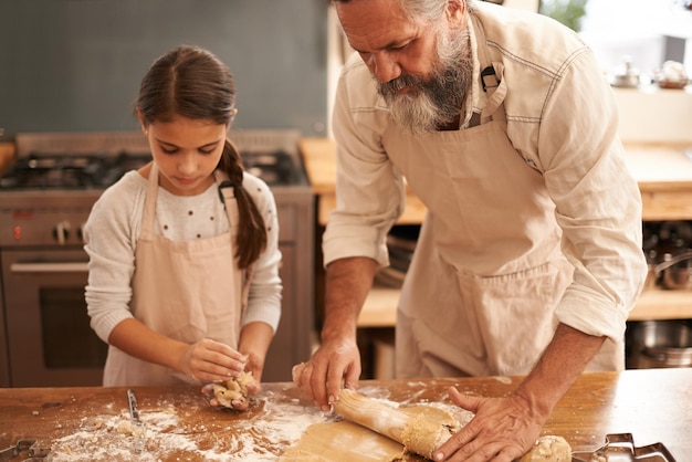 Se toman en serio la repostería Foto de una niña y su abuelo horneando juntos en la cocina
