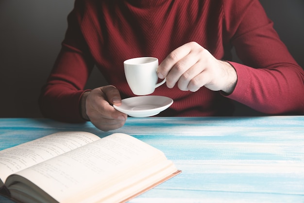 Tomando café e lendo um livro sobre a mesa