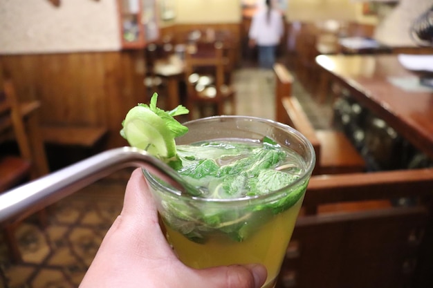 Tomando un cóctel en un vaso de vidrio con hierbas y limón