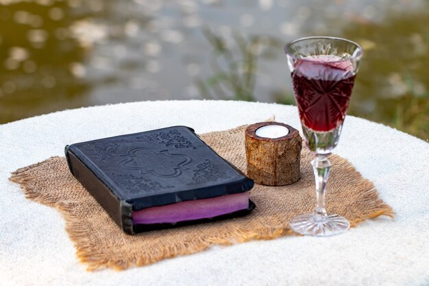 Tomando la Comunión. Copa de vidrio con vino tinto, pan y Santa Biblia en primer plano de la mesa de madera.