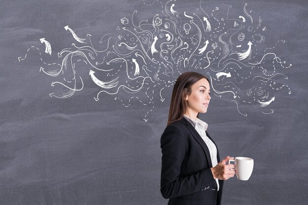 Tomando el concepto de decisión con una mujer de negocios satisfecha con una taza de café con flechas claras en el fondo de la pizarra