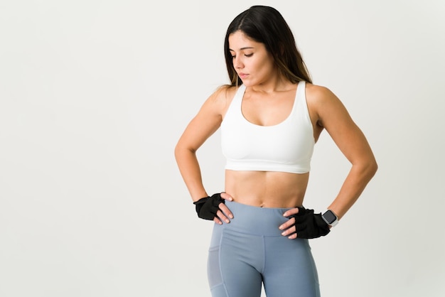 Tomando un descanso después de un entrenamiento fuerte. Hermosa mujer con un cuerpo tonificado sudando después de hacer ejercicio cardiovascular