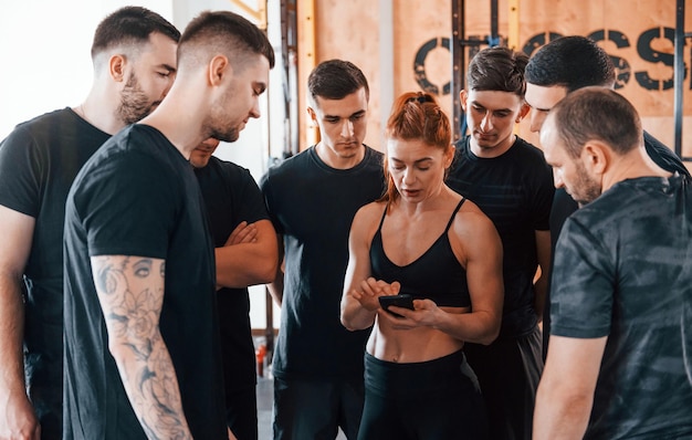 Foto tomando un descanso grupo de jóvenes deportistas tienen un día de crossfit en el interior del gimnasio