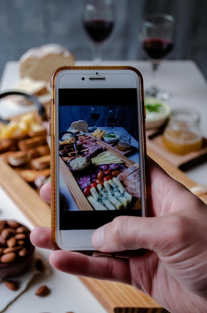 Tomando fotografía de comida servida en la mesa con tu smartphone Charcutería Picada Argentina.