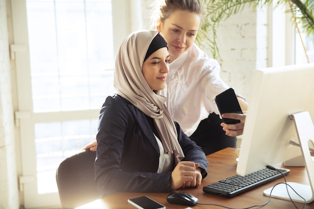 Tomando fotografías con un colega. Hermosa mujer de negocios árabe con hijab mientras trabaja en el espacio abierto o en la oficina. Concepto de ocupación, libertad en el ámbito empresarial, liderazgo, éxito, solución moderna.