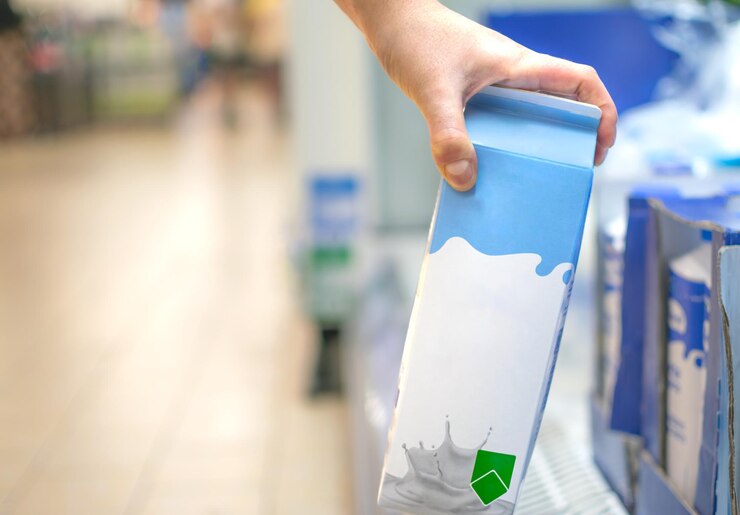 Tomando a mano un cartón de leche del estante del supermercado listo para el consumo