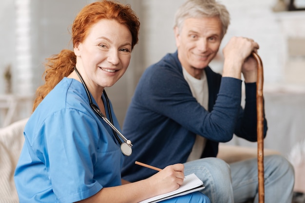 Tomando notas. Aprendeu um médico local produtivo visitando um homem idoso a fim de realizar exames gerais e diagnósticos