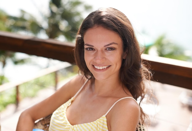 Tomando un poco de sol Retrato de una mujer joven sentada y relajándose afuera de vacaciones