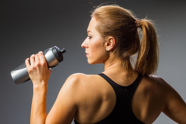 Tomando un refresco Una joven rubia bebiendo agua después de un duro entrenamiento