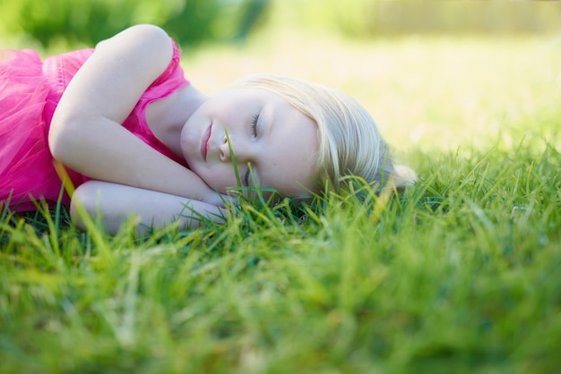 Tomando una siesta bajo el sol Captura recortada de una linda niña durmiendo en el césped afuera