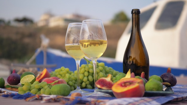 Tomando vino y frutas frescas cerca del mar.