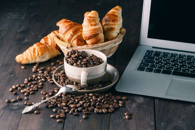 Tomar café e croissants com smartphone e fones de ouvido