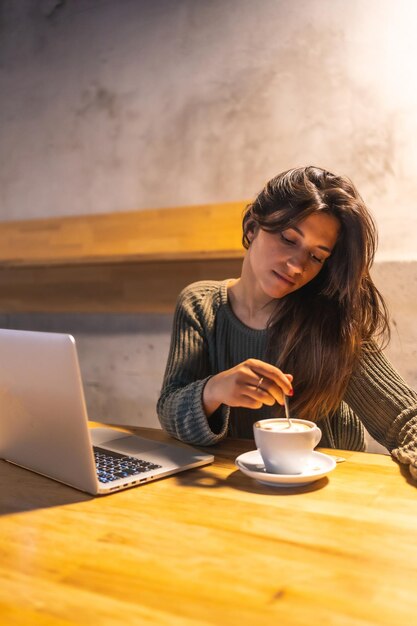 Foto tomar un café hablando por teléfono y trabajando en la computadora