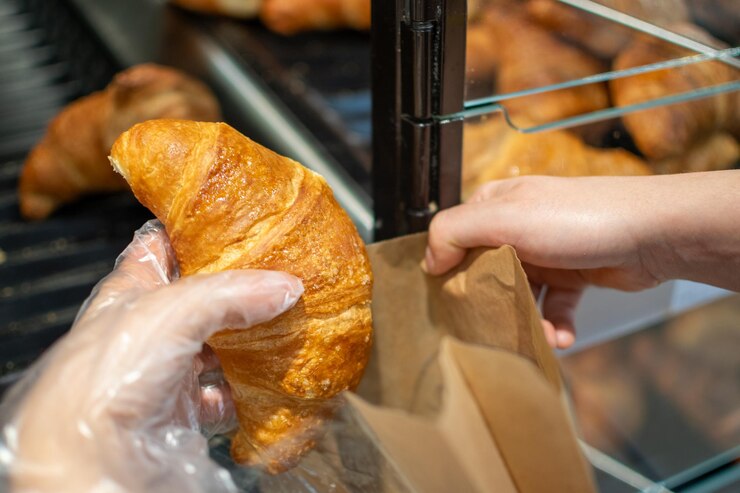 Tomar a mano croissants almacenados para la venta y el consumo pasteles franceses populares
