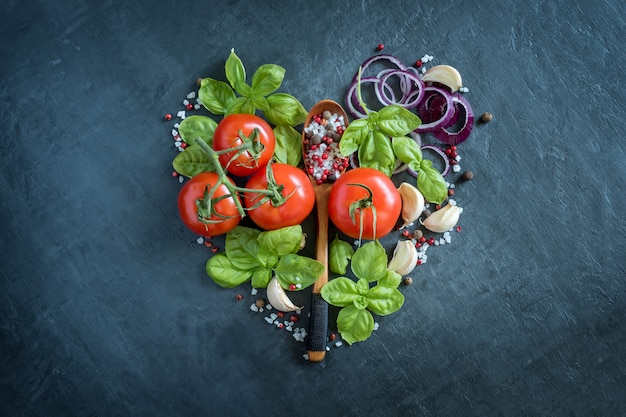 Tomate albahaca ajo y especias en una mesa de piedra en forma de corazón concepto de comida sana.