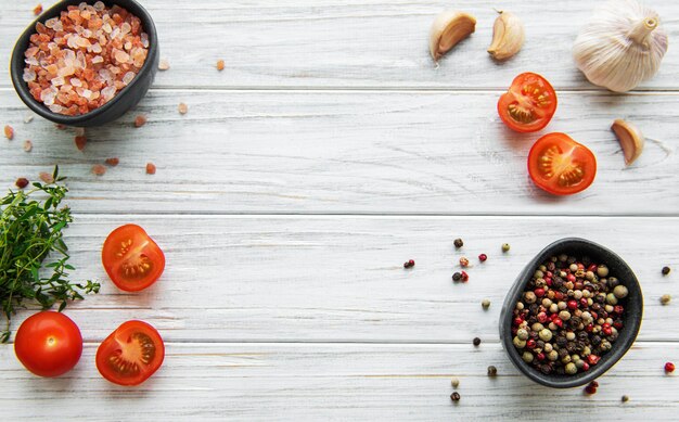 Tomate, albahaca y pimiento con ajo sobre mesa de madera blanca