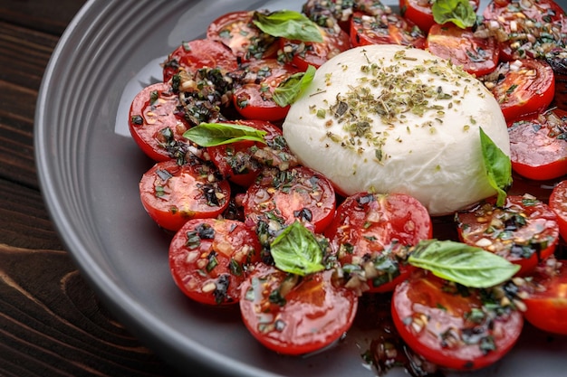 Tomate assado com queijo mussarela em um fundo de madeira