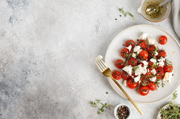 Tomate cereja assado e queijo Feta com óleo de alho e tomilho em chapa branca Espaço de cópia de vista superior