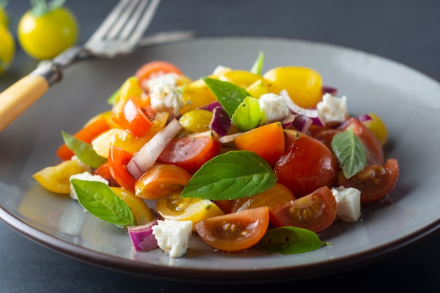 Tomate cereja colorido e salada de manjericão em um prato. Comida saudável de verão.