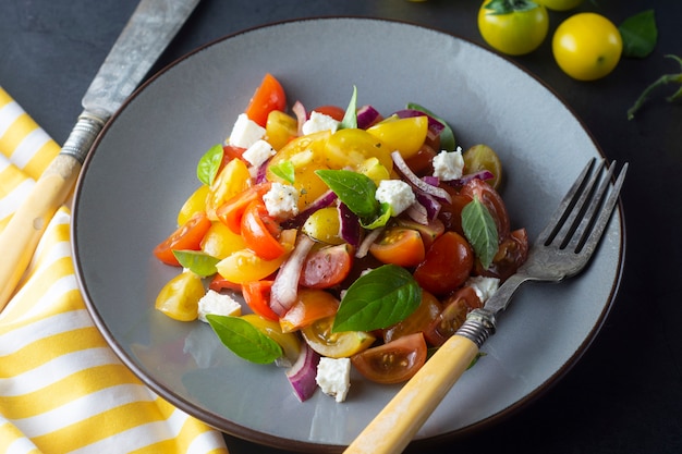 Tomate cereja colorido e salada de manjericão em um prato. Comida saudável de verão.