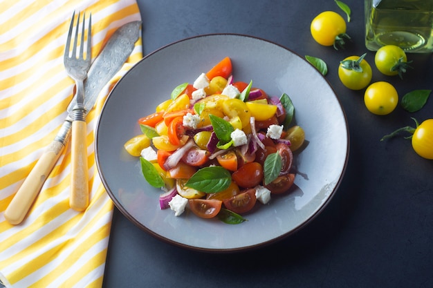 Tomate cereja colorido e salada de manjericão em um prato. Comida saudável de verão.
