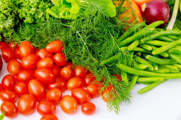 Tomate cereja, ervilha e endro na mesa branca.