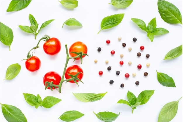 Tomate cereja fresco com folhas de manjericão e diferentes tipos de pimenta em branco