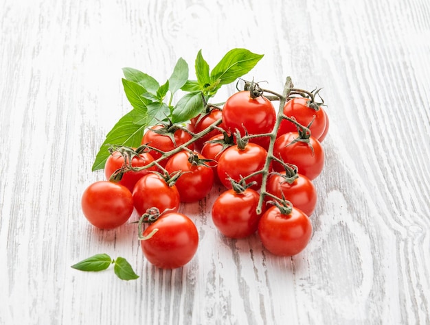 Tomate cereja fresco com manjericão em um fundo branco de madeira Fazenda saudável e vegetal ecológico