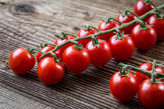 Tomate cereja fresco em um fundo marrom Bando de tomate cereja fresco em uma mesa de madeira