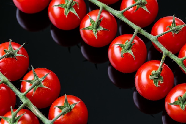 Tomate cereja fresco em um fundo preto Bando de tomate cereja fresco em um fundo preto