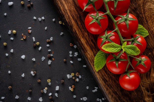 Tomate cereja fresco em um preto com especiarias.