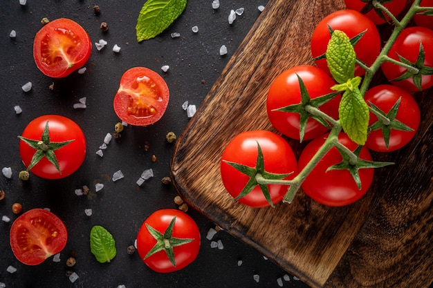 Tomate cereja fresco em uma mesa preta com especiarias.