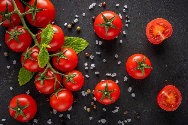 Tomate cereja fresco em uma parede preta com especiarias.