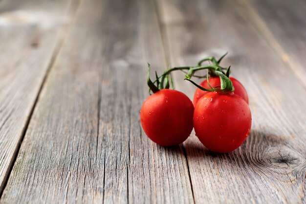 Tomate cereja fresco no galho em fundo de madeira velho. Foco seletivo.