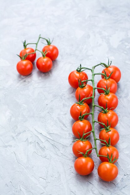 Tomate cereja maduro mel em um galho em um fundo de concreto