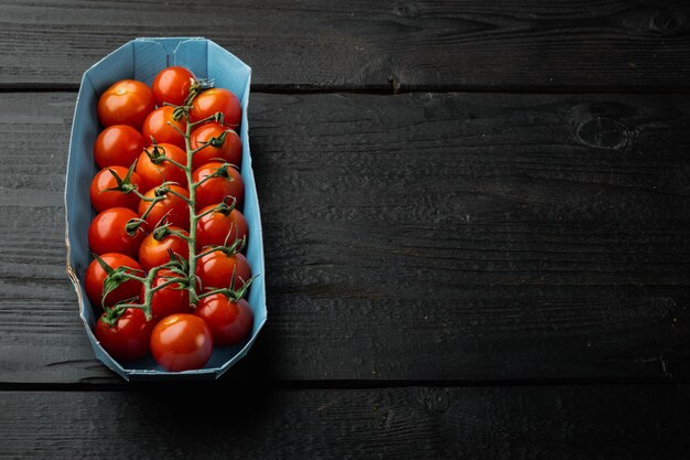 Tomate cereja maduro vermelho, na mesa de madeira preta com espaço de cópia para o texto