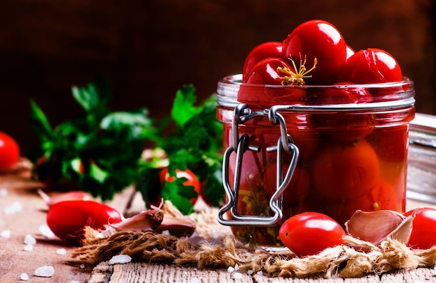 Tomate cereja marinado em um frasco de vidro com foco seletivo de fundo de madeira vintage