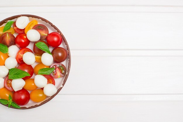 Tomate cereja mussarela bebê e salada de manjericão na vista superior de fundo branco com espaço de cópia Caprese